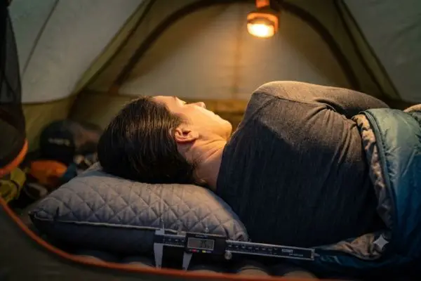 Side sleeper in a tent demonstrating head compression and loft height on the Klymit LUXE pillow.
